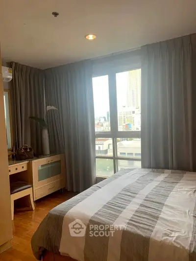 Cozy bedroom with city view, featuring a comfortable bed and elegant curtains.