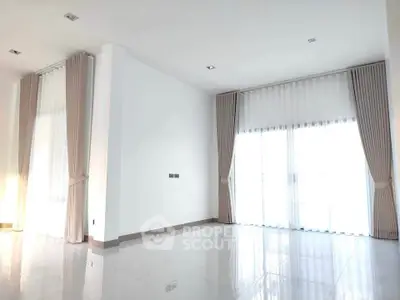 Spacious modern living room with large windows and elegant curtains