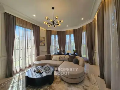 Luxurious living room with elegant decor and large windows, featuring a modern chandelier and stylish furniture.