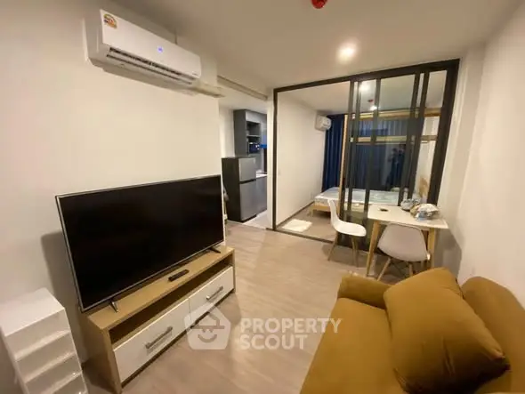 Modern living room with TV, air conditioning, and open view to bedroom.