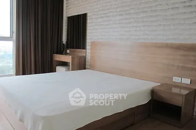 Modern bedroom with wooden furniture and large window offering natural light.