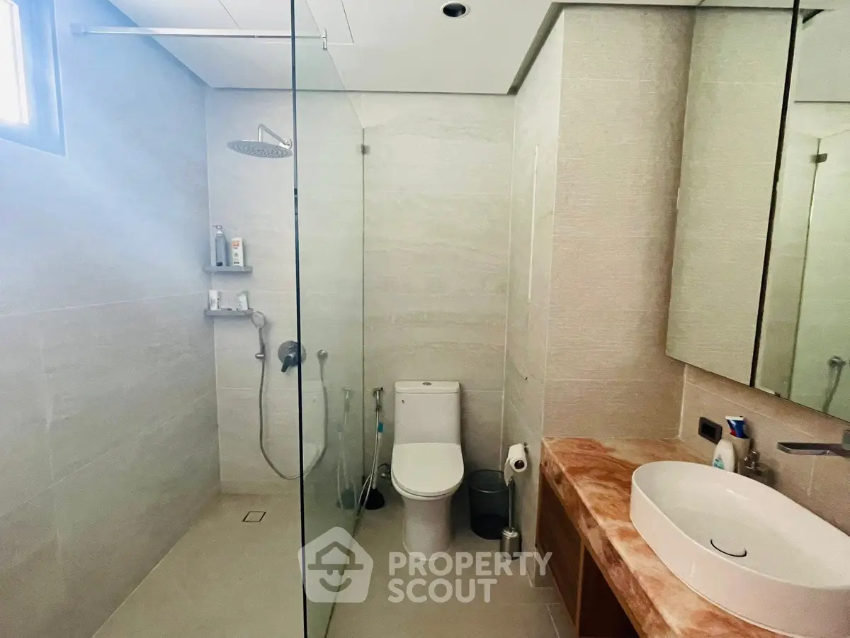 Modern bathroom with glass shower and sleek fixtures in elegant real estate property.