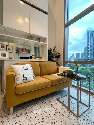Stylish living room with mustard sofa and city view, modern decor and large windows.