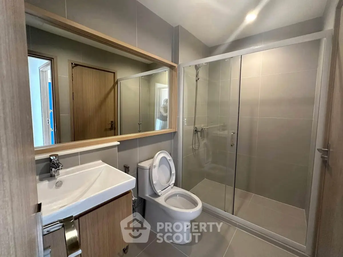 Modern bathroom with glass shower and sleek fixtures in contemporary apartment.