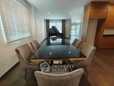 Elegant dining room with luxurious table and grand piano, featuring modern decor and ample natural light.