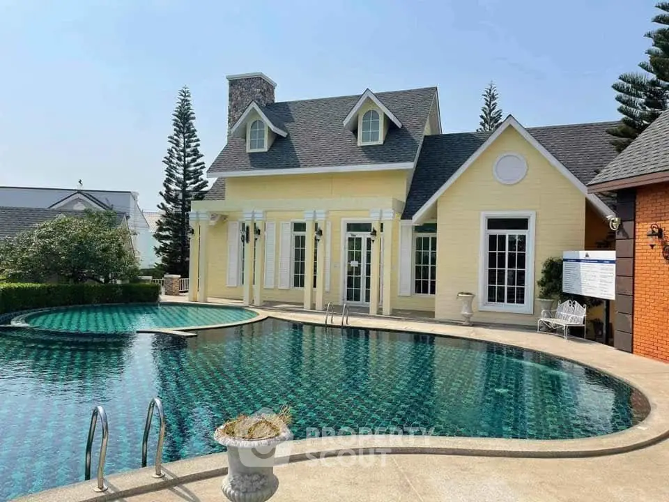 Charming yellow house with elegant pool and lush surroundings, perfect for luxury living.