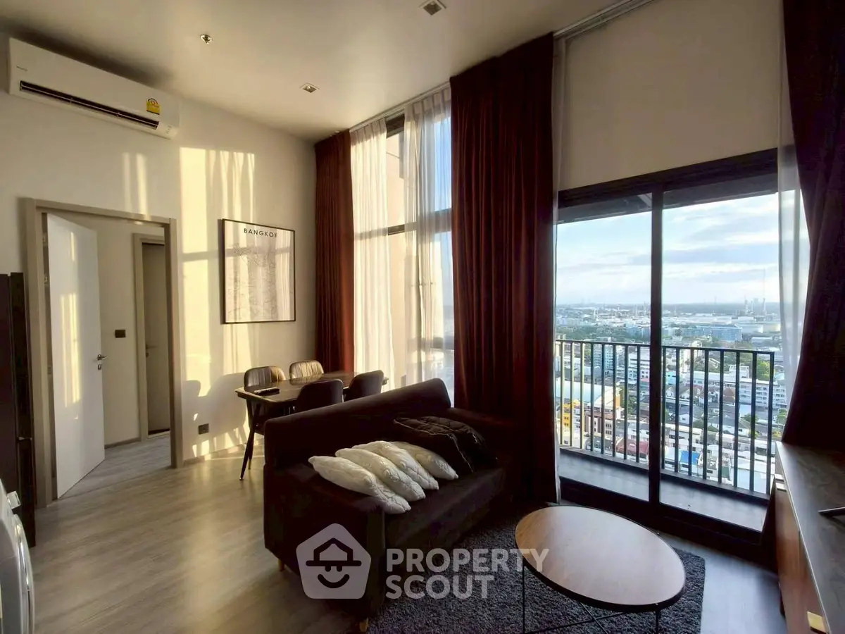 Modern living room with balcony and city view, featuring stylish furniture and natural light.