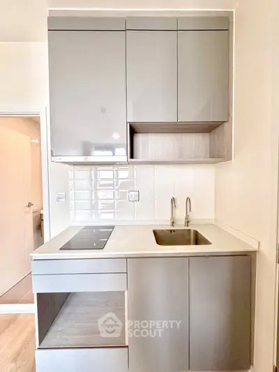 Modern compact kitchen with sleek cabinetry and integrated appliances in a stylish apartment.