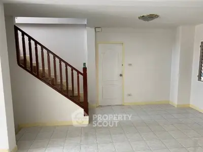 Spacious interior with tiled flooring and wooden staircase, perfect for modern living.
