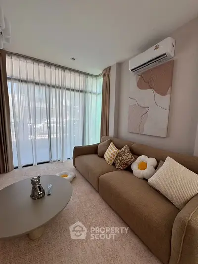 Charming living room with cozy sofa, stylish decor, and large windows for natural light.