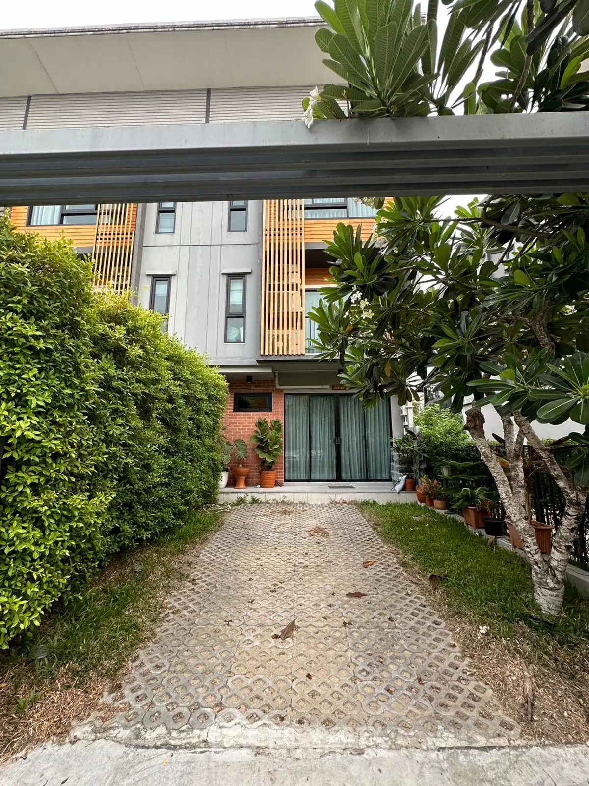 Modern townhouse exterior with lush greenery and spacious driveway
