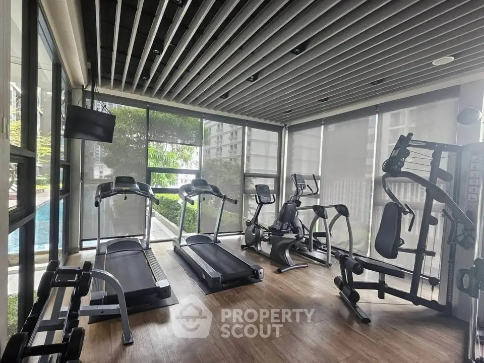 Modern gym with state-of-the-art equipment and pool view in luxury residential building.