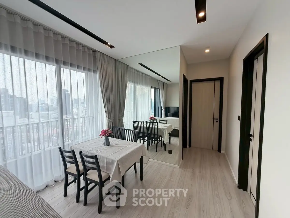 Modern living room with dining area and city view, featuring elegant decor and natural light.