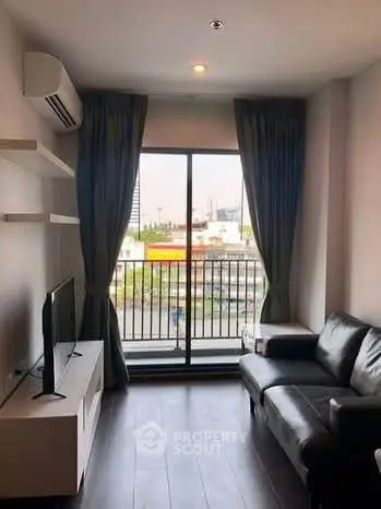 Modern living room with balcony view, sleek furniture, and natural light in urban apartment.