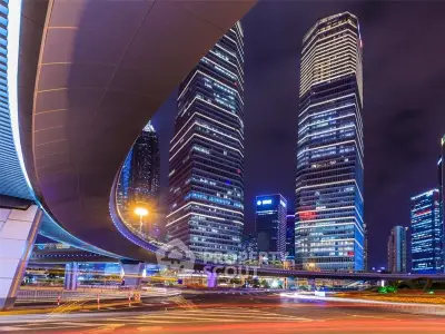 Stunning night view of modern skyscrapers with illuminated cityscape and dynamic highway curves.
