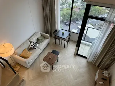 Modern living room with large window and balcony view, featuring stylish furniture and elegant decor.