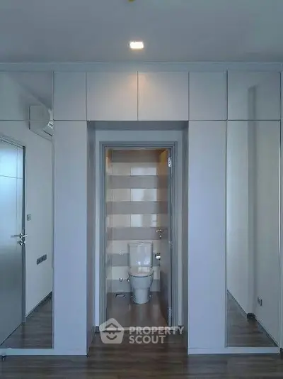 Modern bathroom with sleek design and mirrored walls, featuring a contemporary toilet.
