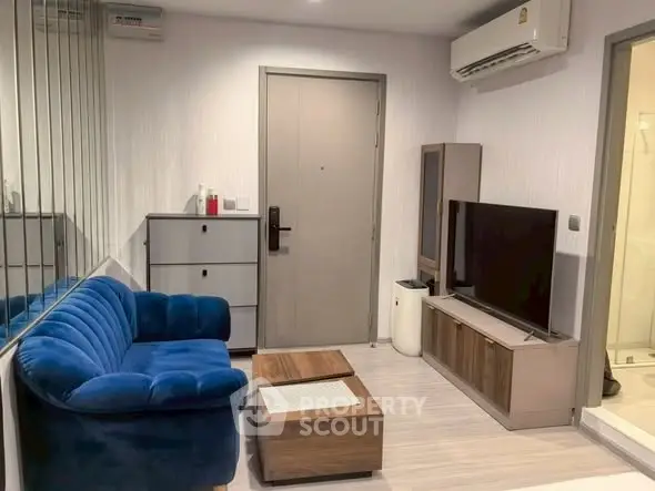 Modern living room with blue sofa, TV, and air conditioning in stylish apartment.