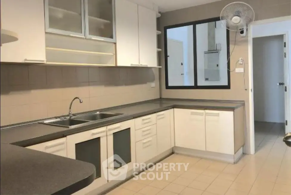 Spacious kitchen with modern cabinetry and ample counter space in a well-lit apartment.