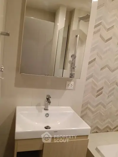 Modern bathroom with stylish sink and mirror, featuring elegant tile design.