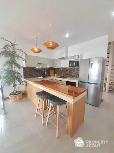 Modern kitchen with island, stylish lighting, and stainless steel appliances