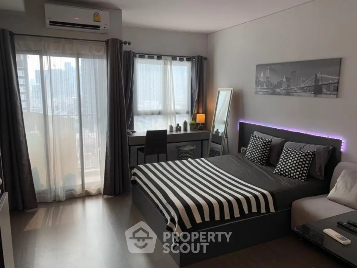 Modern bedroom with stylish decor and city view, featuring a cozy bed and work desk.