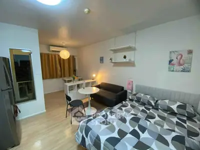Modern studio apartment with stylish decor and open layout, featuring a cozy bed, sofa, and dining area.