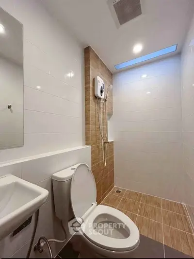 Modern bathroom with sleek design and skylight, featuring a shower and toilet.