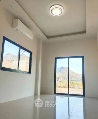 Bright room with mountain view and modern ceiling light, featuring large windows and air conditioning.