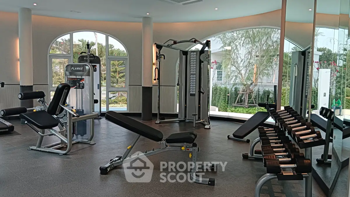 Spacious modern gym with state-of-the-art equipment and large windows offering garden views.