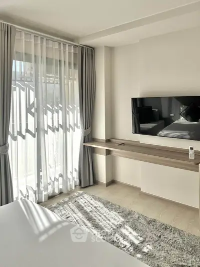 Modern bedroom with large window, stylish curtains, and wall-mounted TV in a bright, airy space.