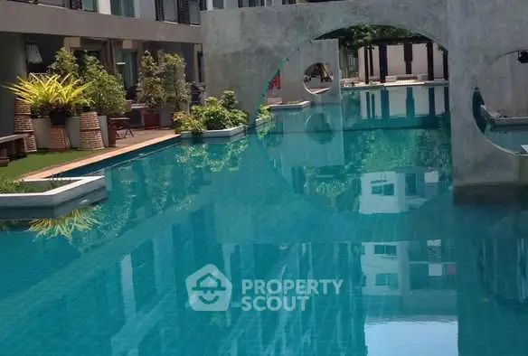 Luxurious modern pool with unique architectural design and lush greenery.