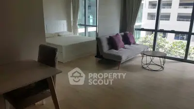 Modern studio apartment with large windows and stylish furnishings in urban setting.