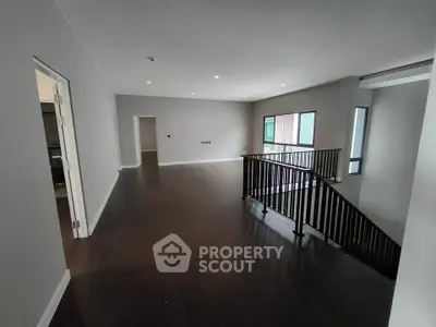 Spacious modern interior with dark wood flooring and large windows, perfect for stylish living.