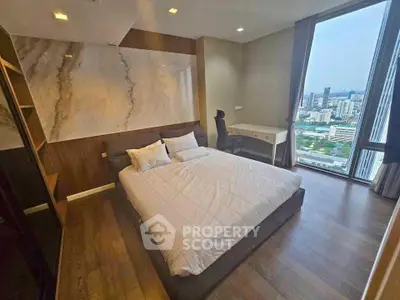 Modern bedroom with city view, featuring stylish decor and large window for natural light.