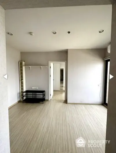 Spacious empty room with modern flooring and neutral walls, ideal for customization.