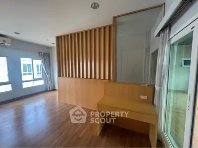 Spacious modern living room with wooden flooring and large windows for natural light.