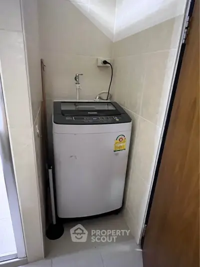 Compact laundry area with modern washing machine in tiled corner space