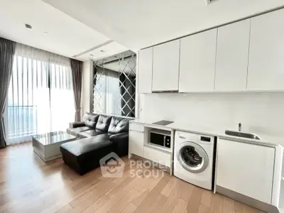 Modern living room with sleek kitchen, washing machine, and large windows for natural light.
