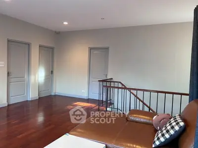 Spacious living area with wooden flooring and cozy seating, ideal for relaxation.