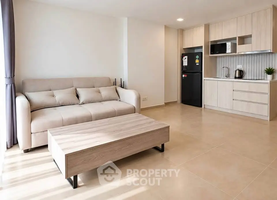 Modern living room with beige sofa and open kitchen layout in a bright apartment.