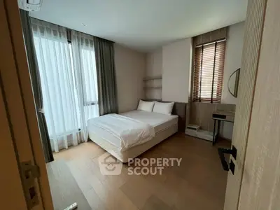 Modern bedroom with natural light and minimalist design, featuring wooden floors and stylish furnishings.