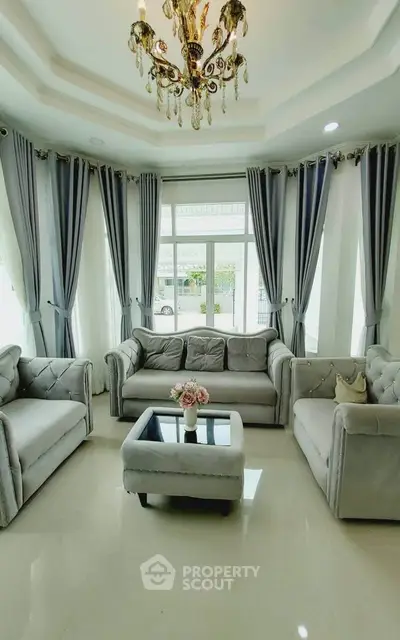 Elegant living room with plush sofas and chandelier, perfect for relaxation.