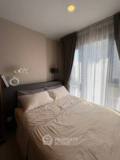 Cozy bedroom with elegant decor and large window offering natural light