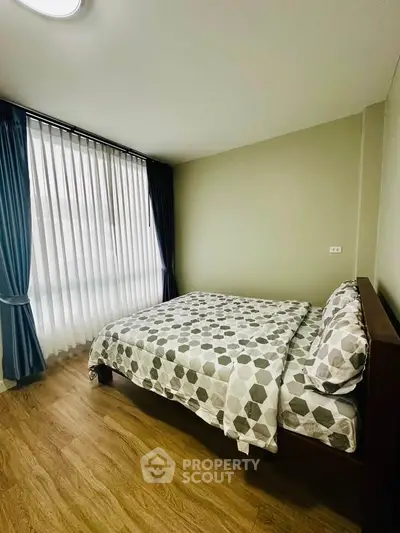 Cozy bedroom with modern decor and large window with curtains, perfect for relaxation.