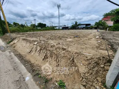 Vacant land plot ready for development with clear skies and surrounding greenery.