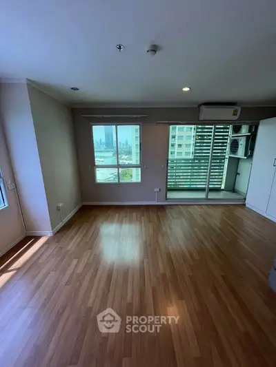 Spacious living room with wooden flooring and balcony access in modern apartment.
