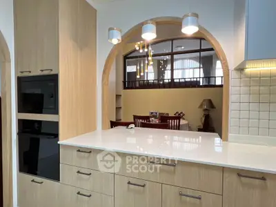 Modern kitchen with open layout and sleek cabinetry, featuring built-in oven and stylish lighting.