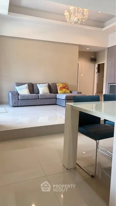 Spacious modern living room with elegant chandelier and sleek furniture design.