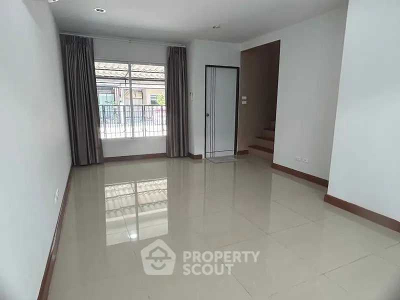 Spacious and well-lit living room with glossy tiled flooring, large windows draped with elegant curtains, and a neutral color palette ready for personalization.